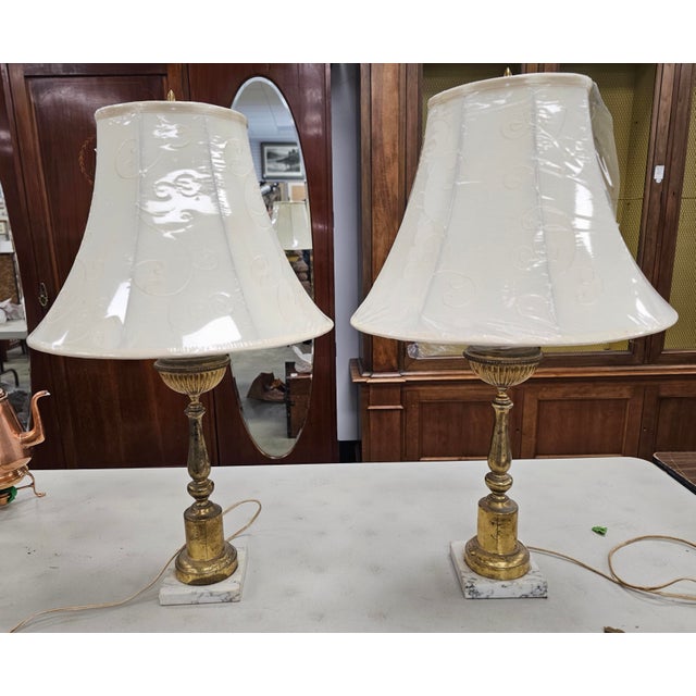 A pair of Mid Century Gilt Metal and Marble Table Lamps. Measures 5" in width x 19" in height to the top of light sockets...