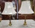 A pair of Mid Century Gilt Metal and Marble Table Lamps. Measures 5" in width x 19" in height to the top of light sockets...