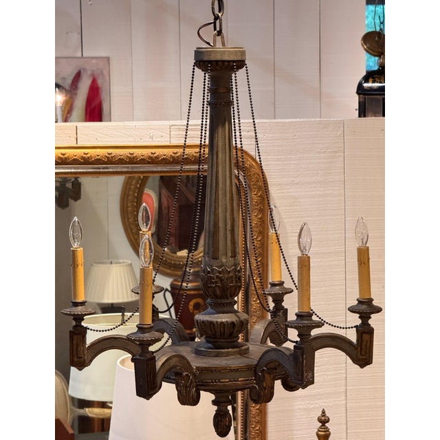Carved and painted wood chandelier with a fluted column rising from acanthus leaves, over scrolled arms holding candle...