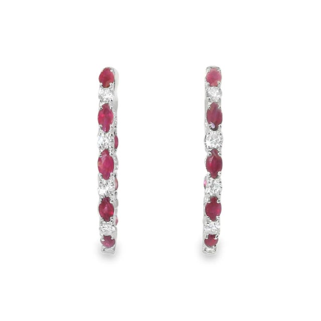 14K White Gold Diamond Ruby Hoop Earrings. This elegant pair features numerous brilliant round diamonds totaling 1.1...