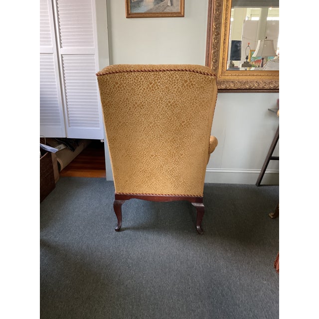 Wing chair with matching ottoman. Newly upholstered in yellow gold designer fabric and rope trim in red and gold colors....