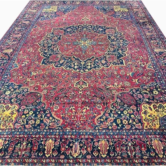 ACTUAL SIZE: 11’9″ x 16’4″ PRIMARY COLOR: Red / Navy AGE: Antique MATERIALS: Wool FOUNDATION: Cotton PRODUCTION:...