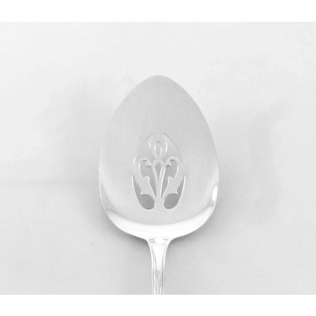 A sterling silver server by Lunt Silversmiths in the Quintessence pattern. The handle has raised flowers and branches and...