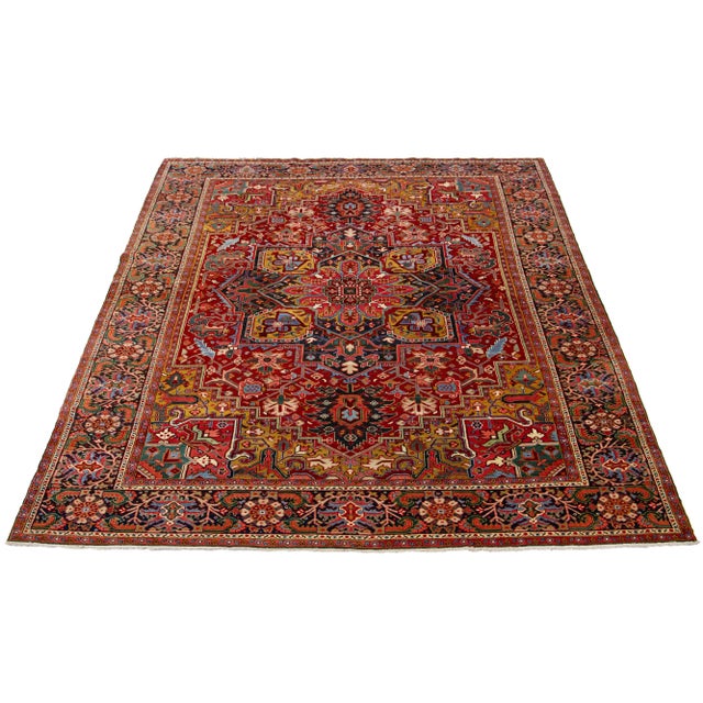 This beautiful antique Heriz hand-knotted wool rug features a red field. The Persian rug highlights a center medallion...
