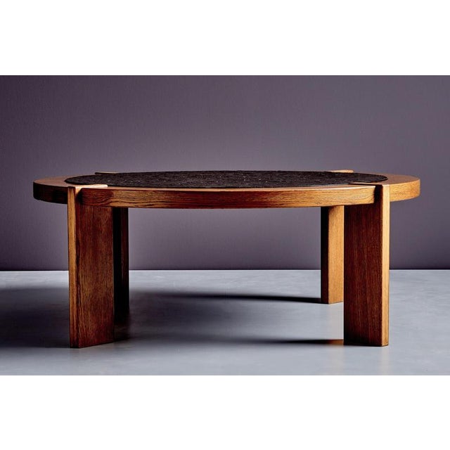 This brutalist coffee table combines a circular slate inset with a solid wood frame, creating a striking contrast between...