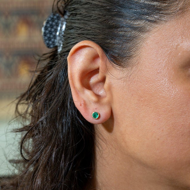 A matched pair of Zambian emeralds glows in lush green in these solid 14K yellow gold bezel-set solitaire stud earrings....