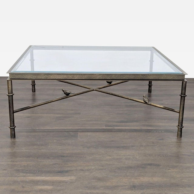 Bronze finish iron table with hammered apron. Stretchers feature 3 resting birds. The tabletop is beveled glass....