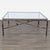 Bronze finish iron table with hammered apron. Stretchers feature 3 resting birds. The tabletop is beveled glass....