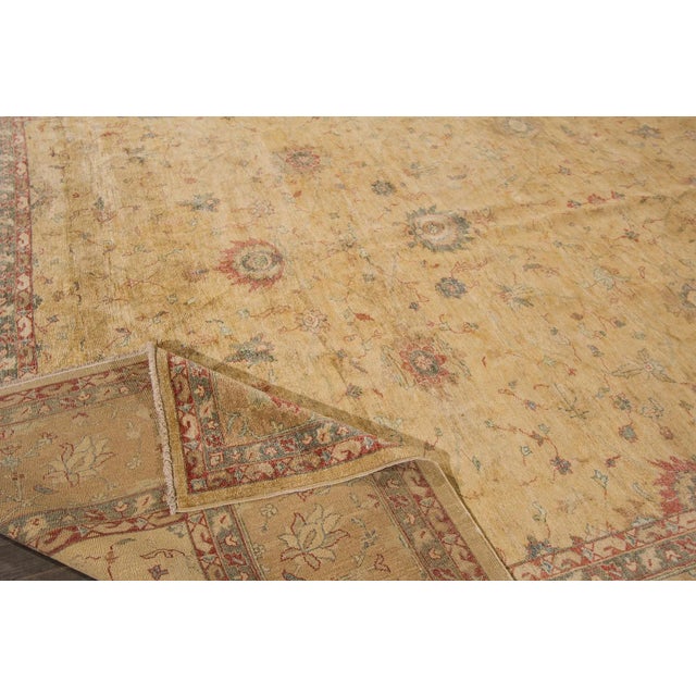 A hand-knotted wool Peshawar rug with a geometric design on a beige field. Accents of red, blue, and ivory throughout the...