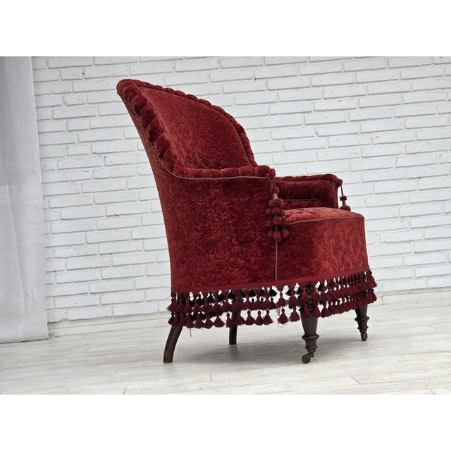 1950s, Danish highback armchair. Red furniture velour, beech wood legs, brass springs in the seat. The chair was...