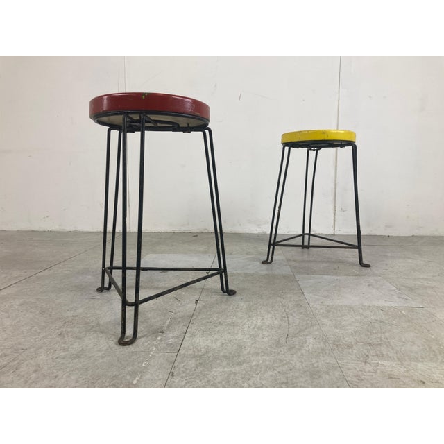 Mid-Century industrial stools with a red and yellow wooden seat and a black metal base. Very much in the style of Belgian...