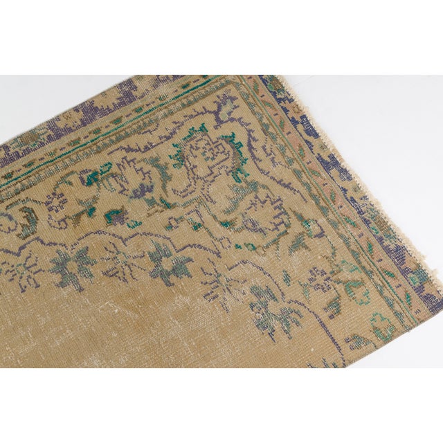 This is a vintage Turkish Oushak rug from the Mid 20th Century. The piece was hand-knotted.