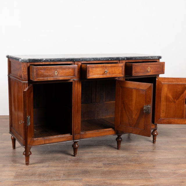 20th-century French mahogany sideboard featuring a three-drawer over three-door configuration and the original marble top....