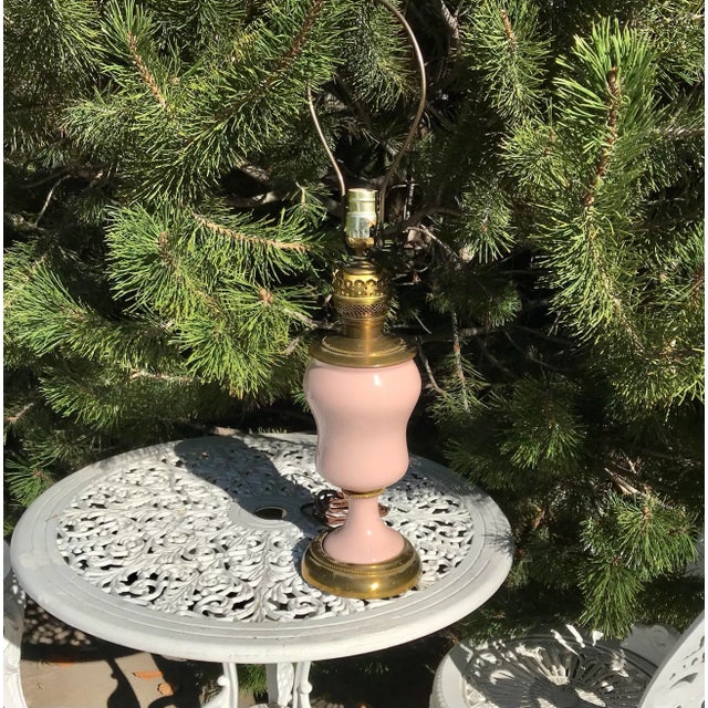 Pale powder pink lamp, with beaded brass trim. Rounded top that tapers to smaller bowl. 19” from base to bulb base.