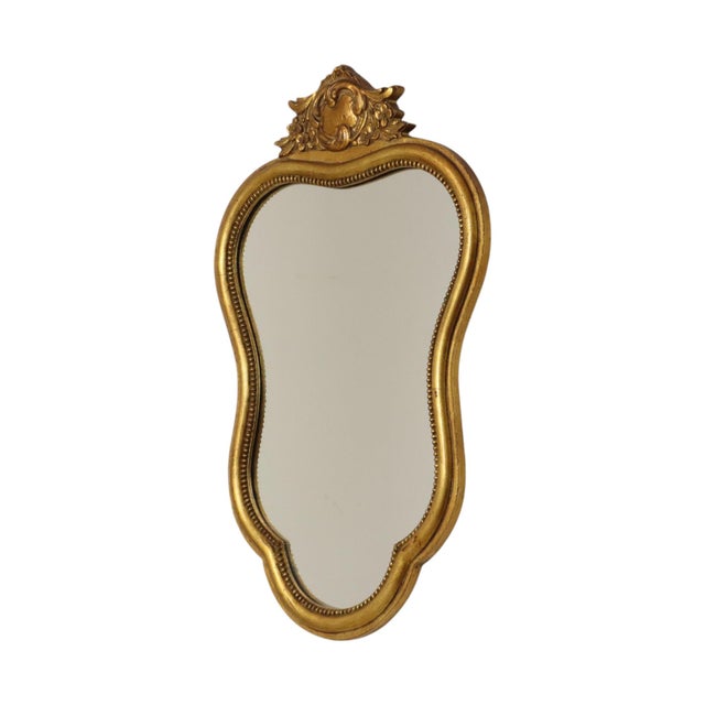 French gold-tone mirror featuring a crest, crafted from wood in a classic Baroque style; the crest is adorned with...