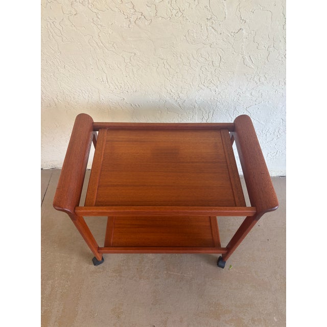 A handsome 1970s serving cart in the Danish Modern style, crafted with a solid teak frame and sculpted, integrated...