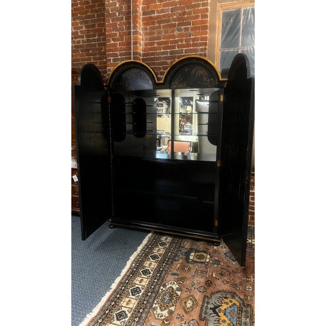 A stunning late 19th century English Chinoiserie bar cabinet featuring richly detailed gilt landscape scenes over a deep...