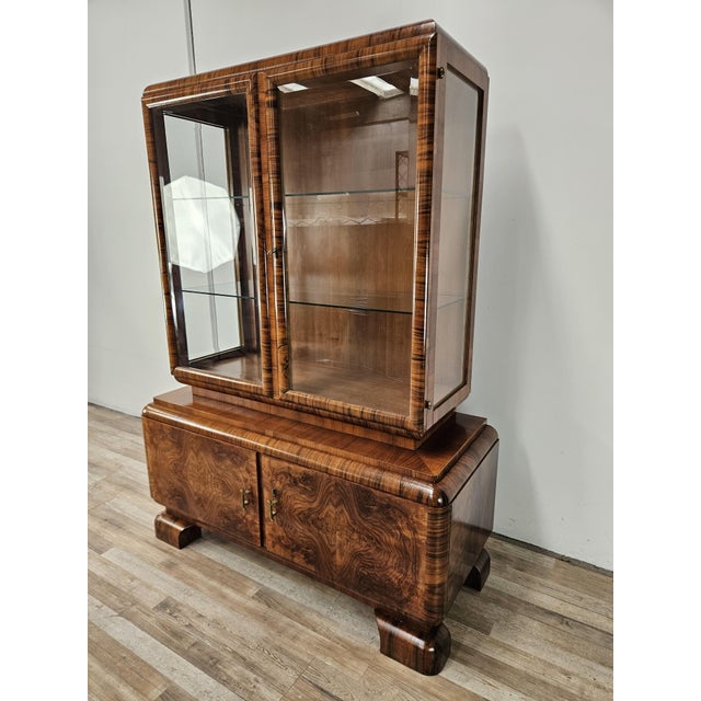 A splendid vintage display cabinet dating back to the 1940s, featuring a refined Art Deco style and rich walnut grain,...