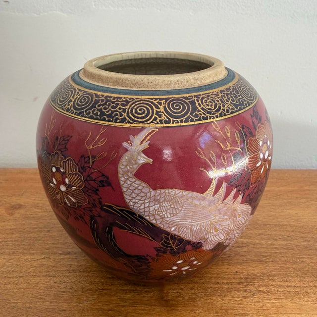 Small vintage chinoiserie ceramic vase with a white peacock and gold florals on a deep burgundy ground. Ornate shoulder...