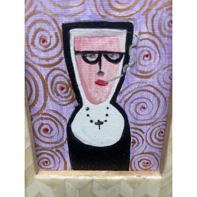 A whimsical portrait of a Nun smoking a cigarette on a lavender background with a swirl pattern, in a herringbone Rame...