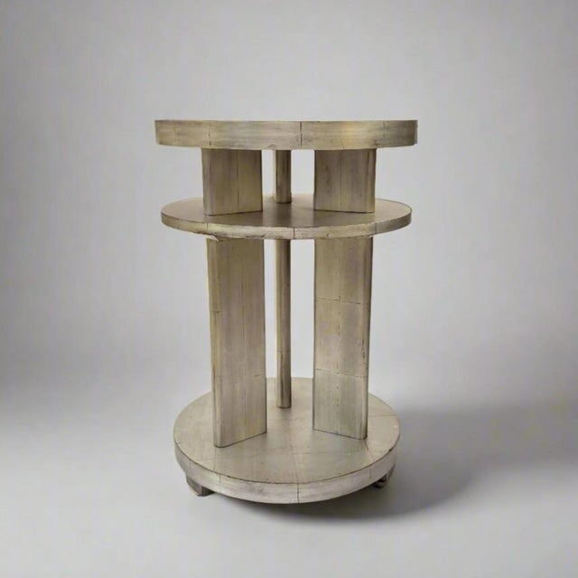 An Art Deco two-tiered side table in white gold leaf. The silvery reflection has a decidedly enchanting effect in an...