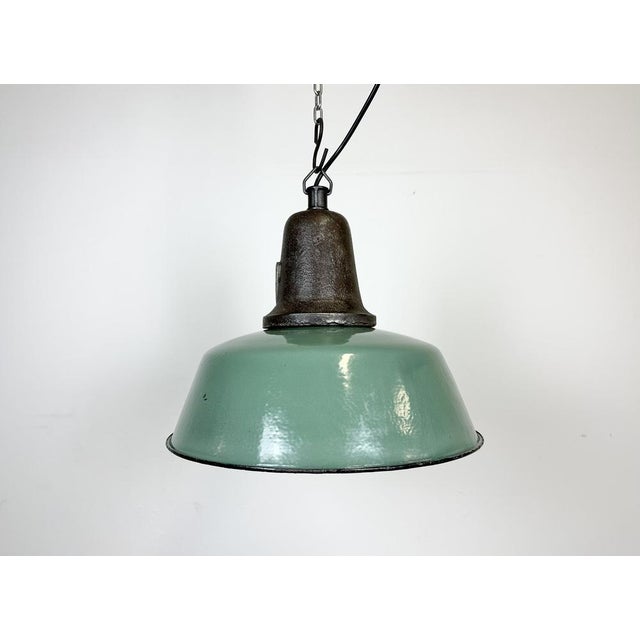Industrial green enamel pendant light made in Poland during the 1960s. White enamel inside the shade. Cast iron top. The...
