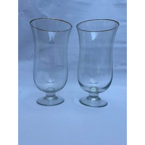 A matching pair of round transparent blown glass footed candle hurricanes with attached taper candle holder and a simple...
