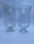 A matching pair of round transparent blown glass footed candle hurricanes with attached taper candle holder and a simple...