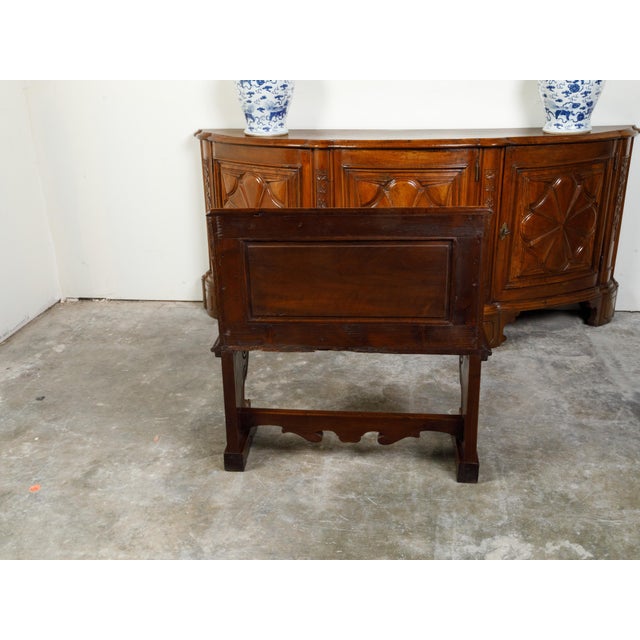 An Italian walnut hall bench from the 19th century, with carved back, voluted arms and stylized paw feet. Created in Italy...