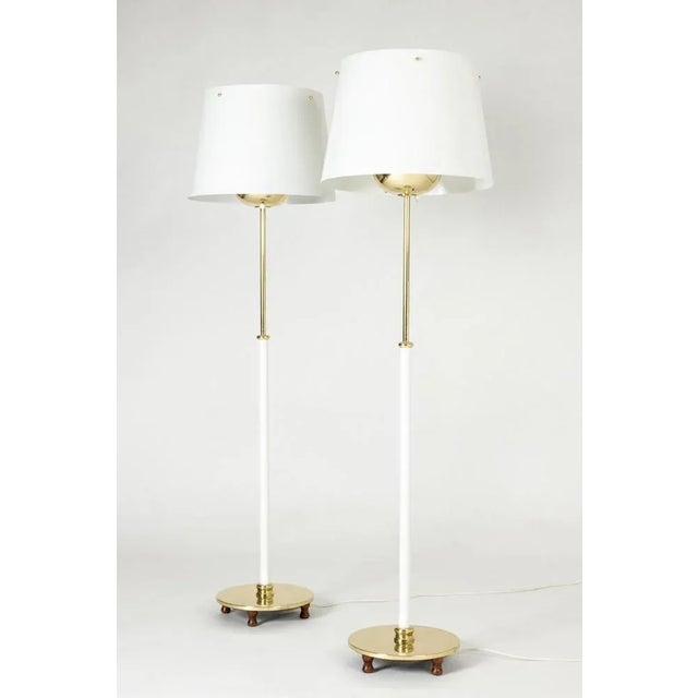 Pair of elegant brass floor lamps by Josef Frank, stems lacquered white on the bottom half. Metal shades with brass...