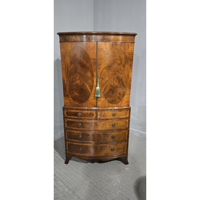 A superb small proportions bow front inlaid linen press, five drawers below two door cabinet with brass slamming strip,...