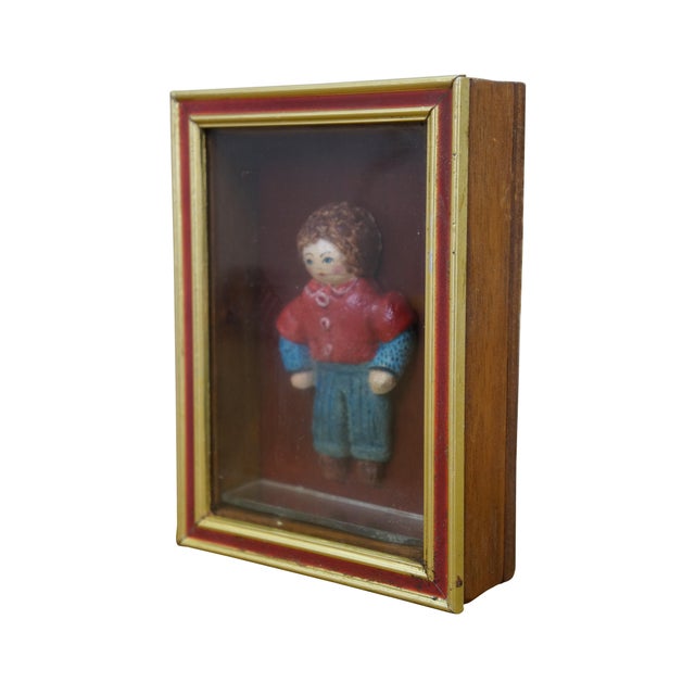 Vintage folk art shadowbox composition doll figurine of a young boy in a red collared shirt and blue jeans. Framed in oak...