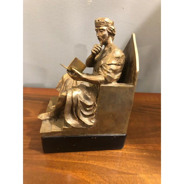 The gilded bronze sculpture of this King seated on his throne, wearing his crown, while he is absorbed in reading a book...