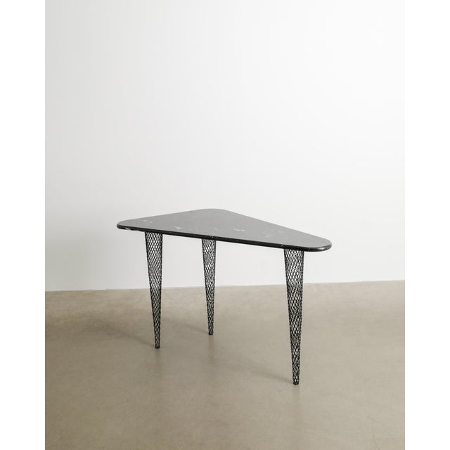 A rare and contemporary "45 degrees north latitude" tripod console table with a black and white decorative marble top on...