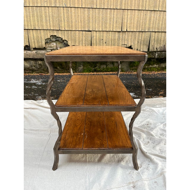 A single three tier wrought iron end table with three wood shelves. Wood top 17.5 x 27.5”, middle shelf 16.5 x 26.5”,...