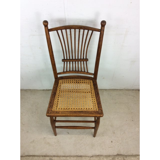 This antique accent chair features hardwood construction, original oak finish, unique spindle back and caned seat.