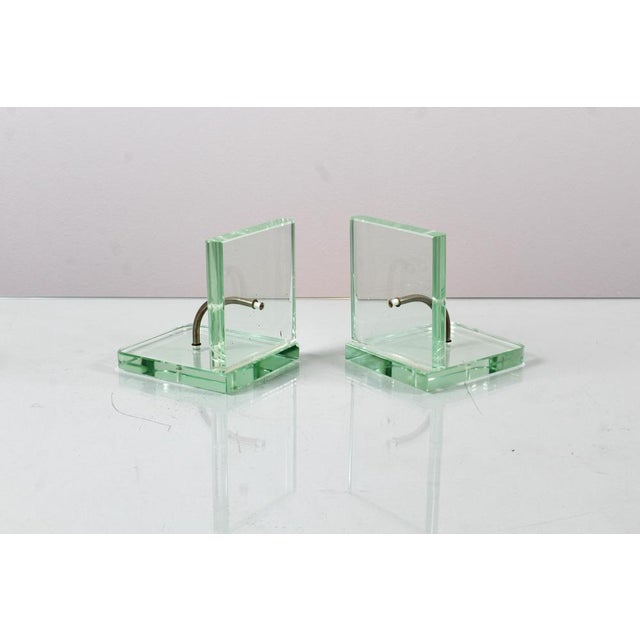 Set of 2 bookends in thick Nile green glass, with curved tubular metal structural element. In the style of Pietro Chiesa...
