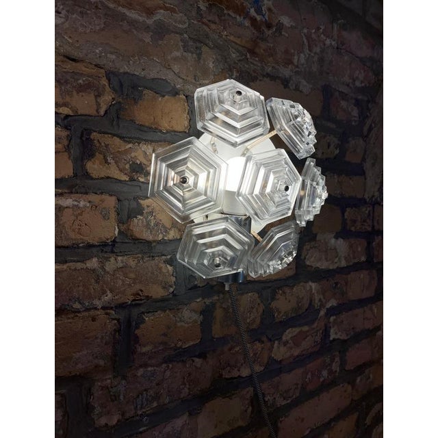 This gdr wall lamp forms a curve made up of seven hexagonal elements. This creates a structure resembling an ice crystal....