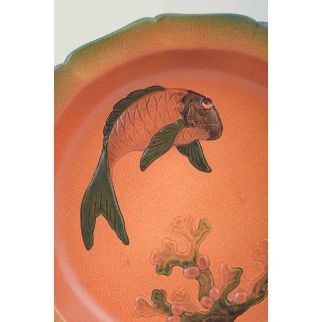 Ipsens Enke, Denmark Large ceramic dish with relief decoration of fish and coral. Orange glaze with a soft green rim....