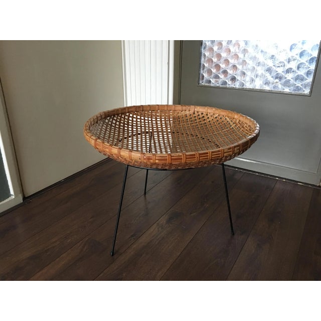 This mid-century side table has a rattan basket top for magazines.