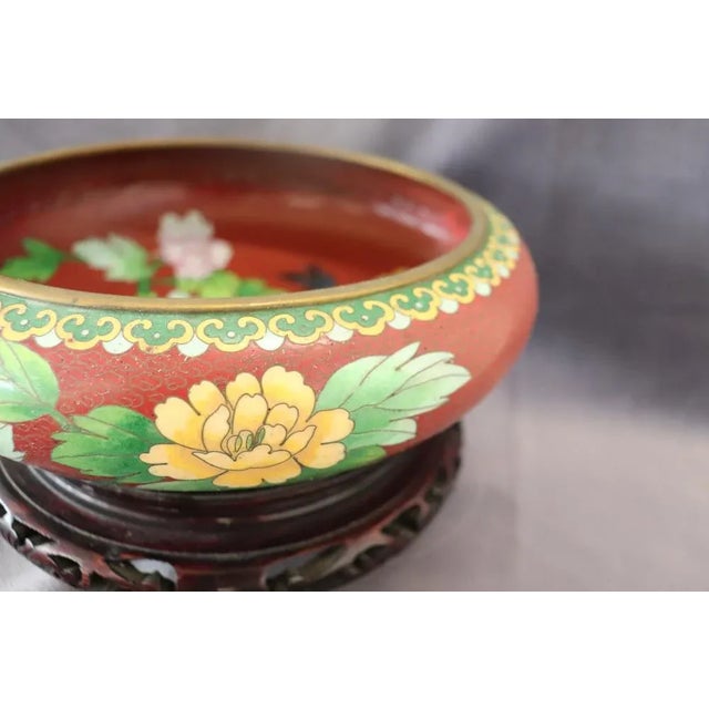 Beautiful Vintage cloisonne bowl, with carved teak stand, circa 1980s. The bowl has a rust red background with an overall...