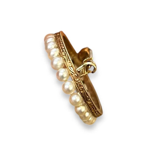 An elegant brooch featuring a delicate arrangement of lustrous pearls, set in a graceful oval shape. The pearls are...