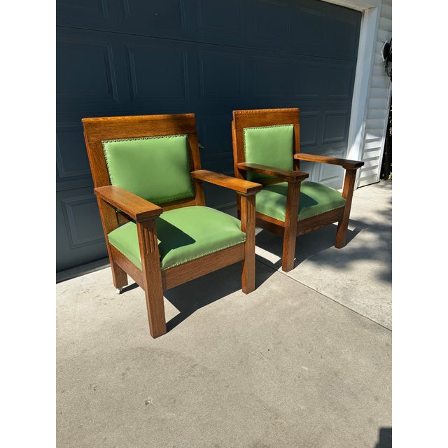 Sturdy pair of Mission style armchairs. Constructed from solid oak with a rich wood grain. Each chair has green leather...