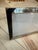 A rectangular picture frame with glossy black corner accents, fine ribbed detailing, and a slim silver border around the...