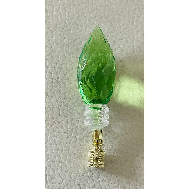 Multifaceted green acrylic candle bulb on brass base as lamp finial.