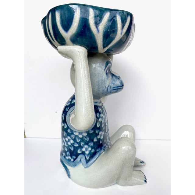 This item is a vintage Chinoiserie-style blue and white porcelain monkey figurine dish. A seated monkey figure wearing a...