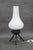 A mid-century table lamp produced in 1960s czechoslovakia, combining a sculptural white glass shade with a modern black...