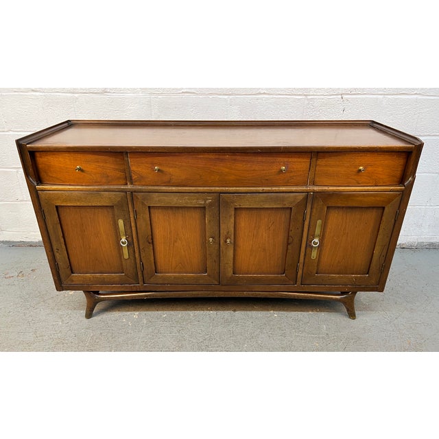 Elevate your space with this stunning Mid-Century Modern sculpted walnut buffet, a timeless statement piece that embodies...