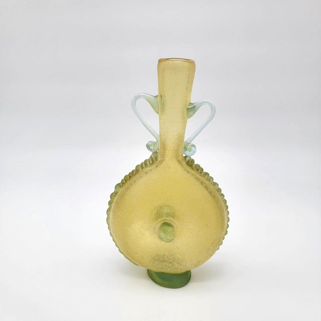 This vintage art glass amphora vase features a unique scavo texture along its sides and applied handles. The yellow and...