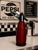 Glossy red vintage soda siphon with black and chrome top assembly, styled with bold retro café character. A striking bar...